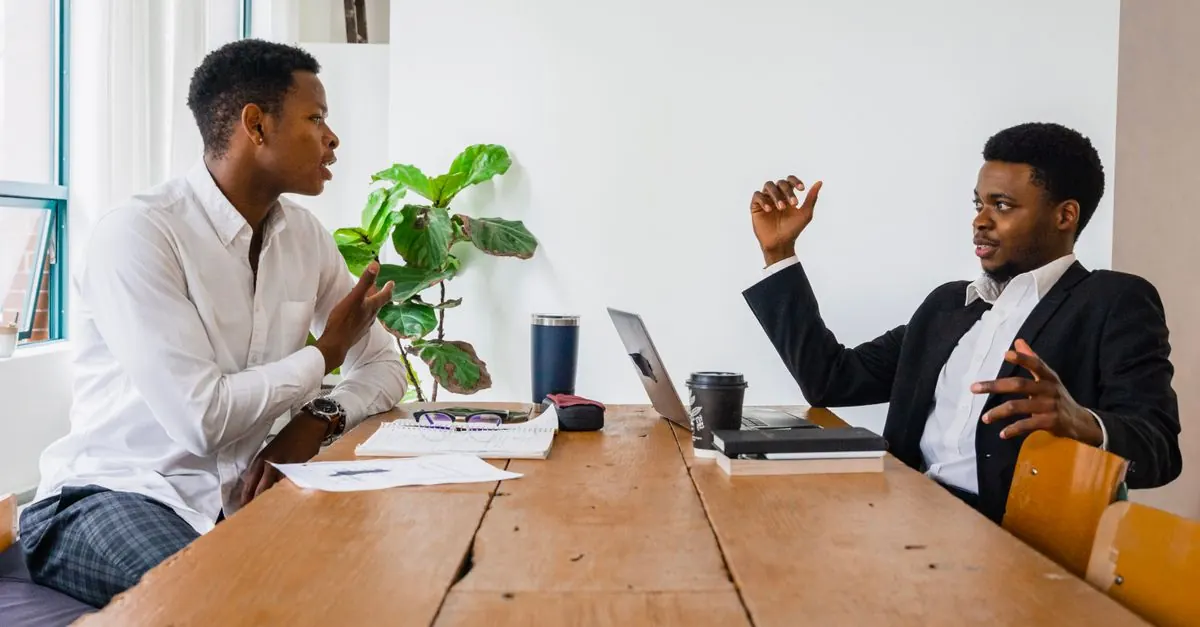 Two people having a friendly professional conversation at a small business table